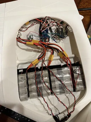 Open center bay: film-wrapped packs of cylindrical cells, red and black wiring, yellow connectors and circuit boards